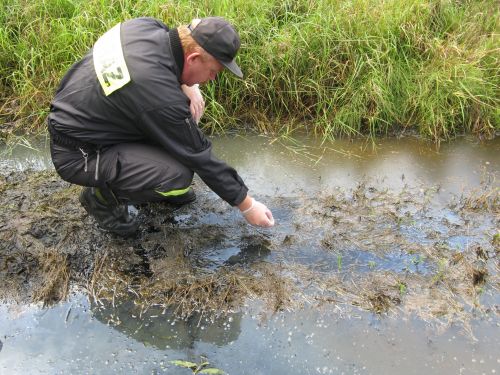 strażak pobiera probki z rzeki - KW PSP w Poznaniu