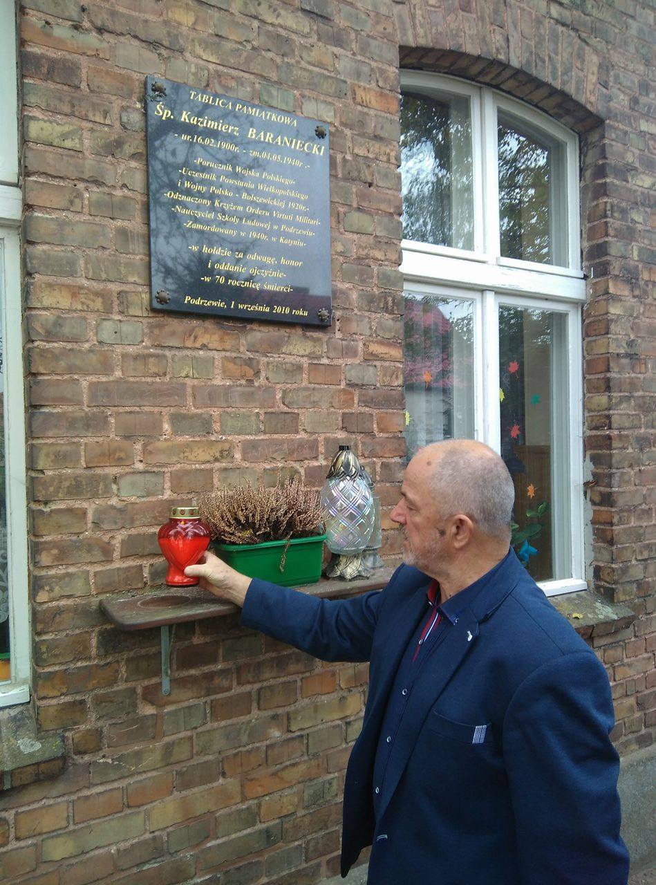 Marian Zaglaniczny w Podrzewiu pod tablicą pamiątkową Kazimierza Baranieckiego - kierownika tamtejszej szkoły zamordowanego w Katyniu.