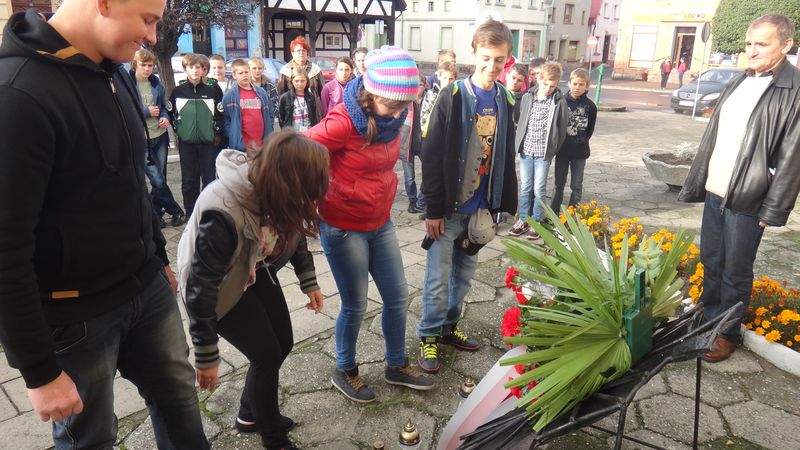 Uczniowie SP i Gimnazjum w Poniecu zapalili znicze pod tablicą na ścianie Ratusza